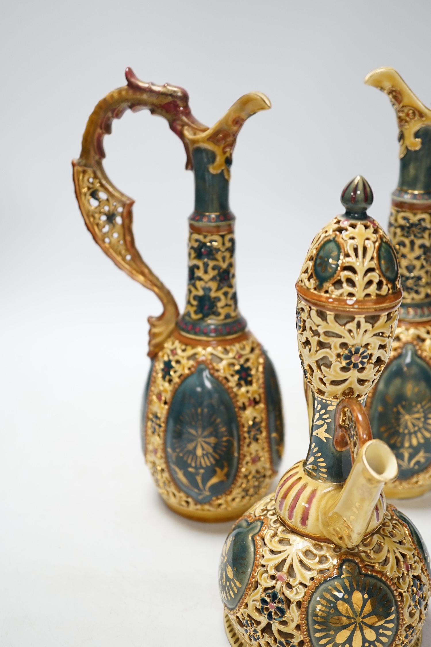 A pair of Zsolnay ewers and a similar ewer with cover, tallest 30cm high